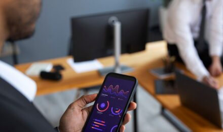 Smartphone displaying AI investment app dashboard next to printed financial plan document